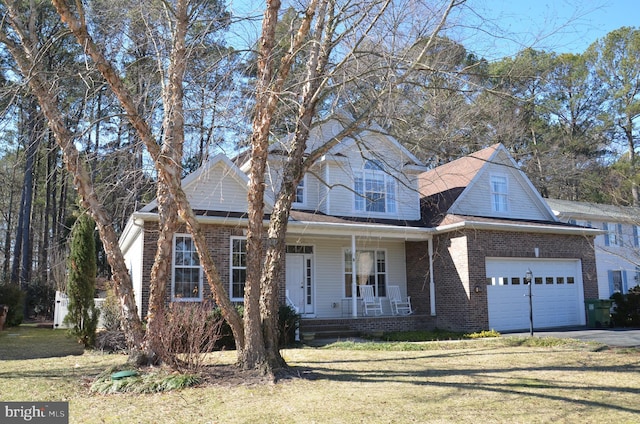 view of front of property featuring driveway, covered porch, a front yard, a garage, and brick siding