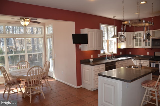 kitchen featuring a kitchen bar, a sink, dark countertops, white cabinetry, and appliances with stainless steel finishes