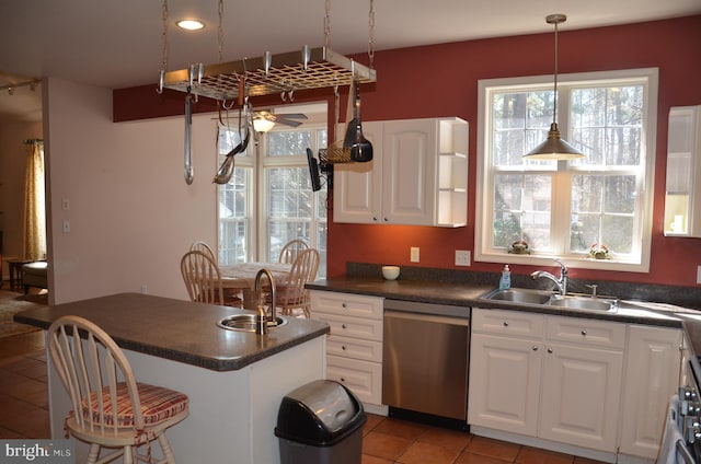 kitchen with dishwasher, dark countertops, white cabinets, and a sink