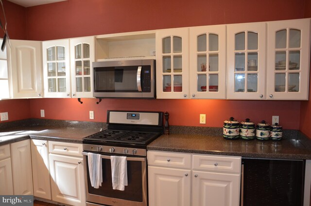 kitchen with dark countertops, appliances with stainless steel finishes, beverage cooler, and white cabinetry