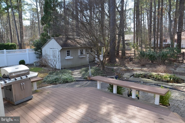 deck featuring an outdoor structure, a storage unit, fence, and grilling area