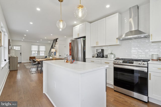 kitchen featuring tasteful backsplash, stainless steel appliances, wall chimney exhaust hood, and light wood-style floors