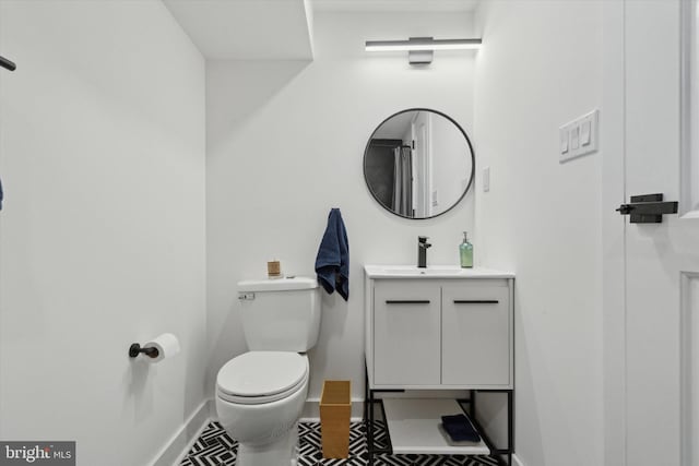 bathroom with baseboards, toilet, and vanity