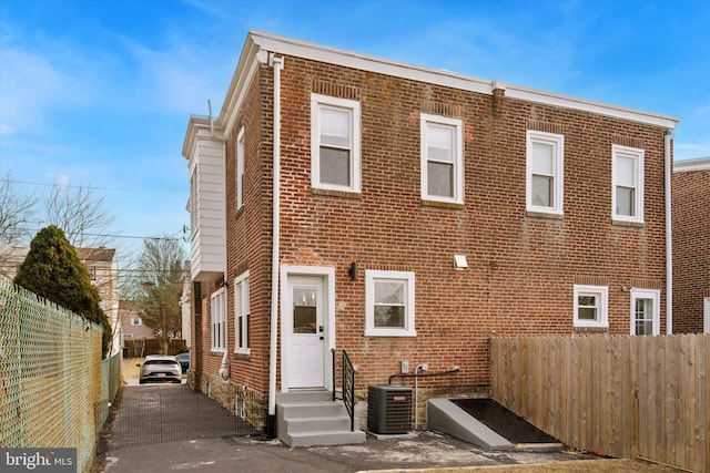 exterior space with brick siding, central AC, entry steps, and fence