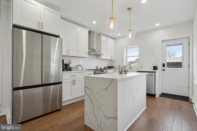 kitchen featuring white cabinetry, wall chimney range hood, dark wood-style floors, and appliances with stainless steel finishes