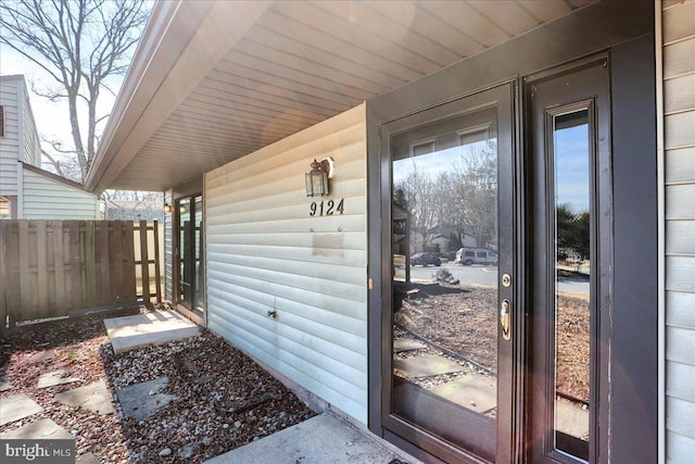 property entrance featuring faux log siding and fence