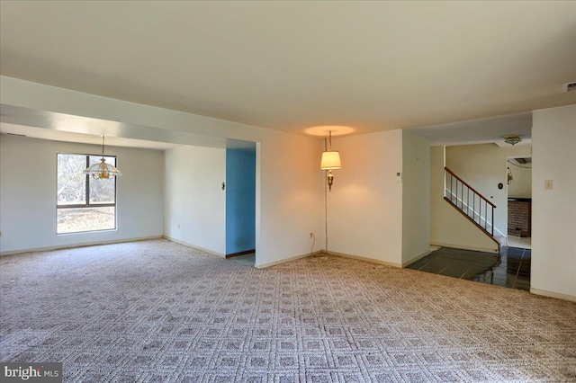 carpeted empty room with visible vents, baseboards, and stairs