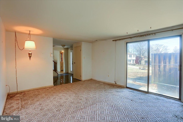 empty room with stairway, baseboards, and light colored carpet