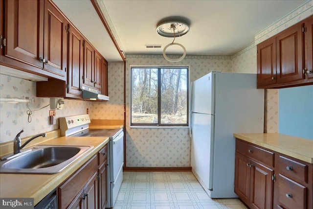 kitchen with visible vents, a sink, white appliances, wallpapered walls, and light floors