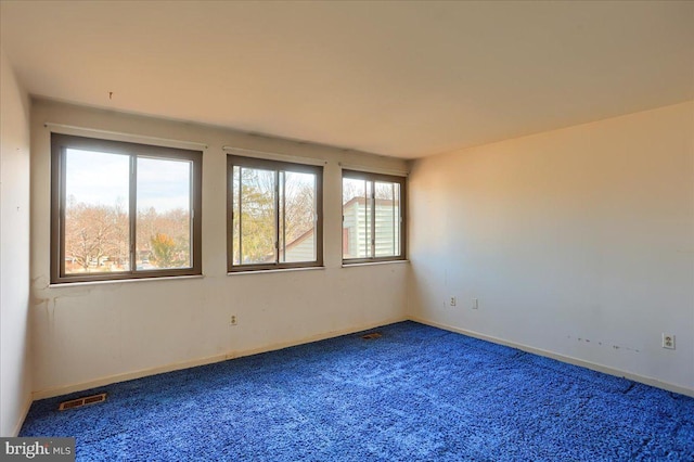 carpeted spare room with visible vents and baseboards