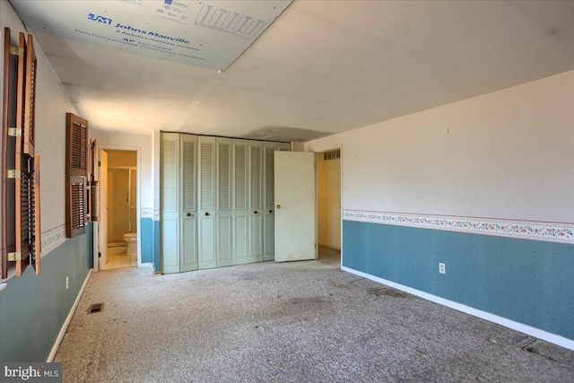 unfurnished bedroom featuring visible vents, carpet floors, baseboards, and ensuite bath