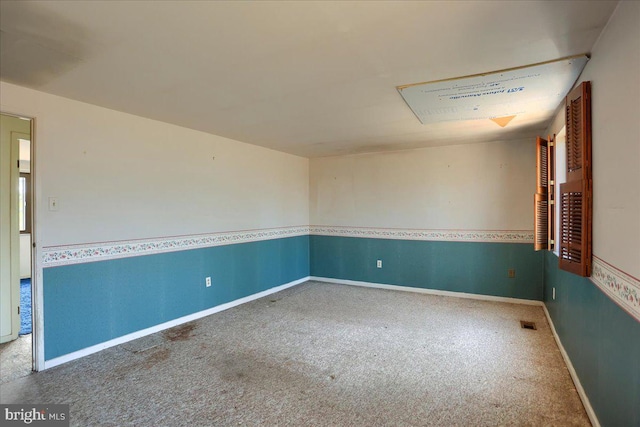 carpeted spare room featuring visible vents and baseboards