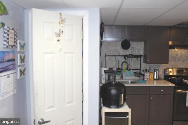 kitchen featuring electric range, a drop ceiling, a sink, dark brown cabinets, and backsplash