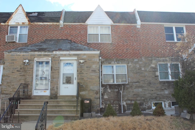 townhome / multi-family property featuring brick siding, stone siding, cooling unit, and a shingled roof