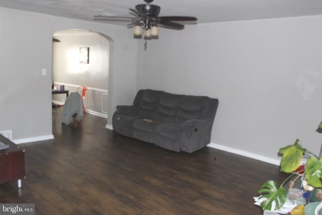 living area with baseboards, arched walkways, and wood finished floors