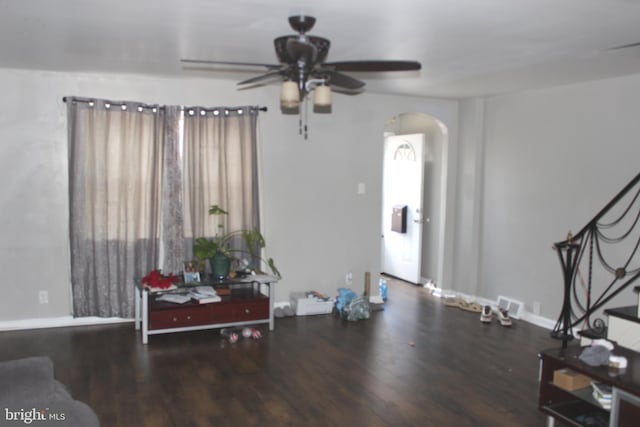 interior space with arched walkways, baseboards, a ceiling fan, and wood finished floors