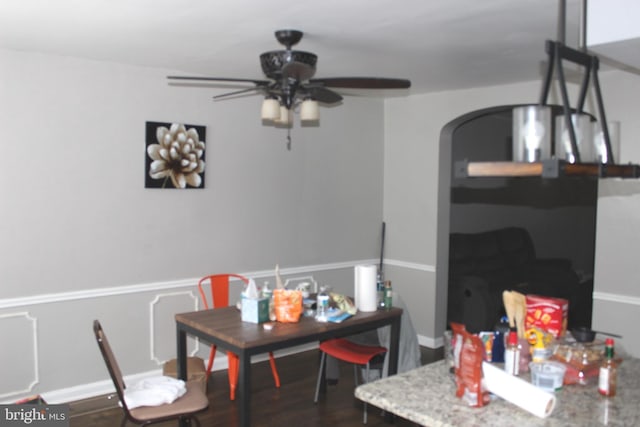 dining room with arched walkways, dark wood-style floors, and a ceiling fan