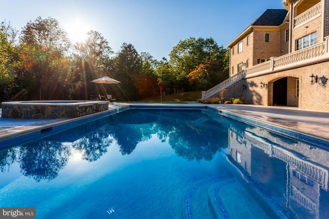 pool with a patio, an in ground hot tub, and stairs