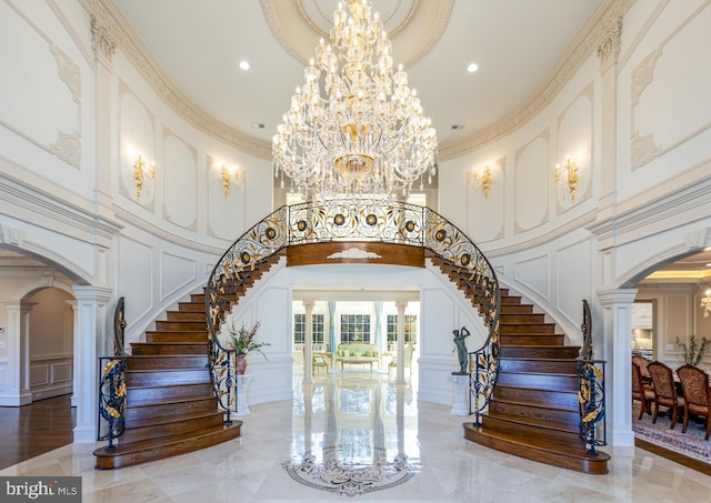 stairs with arched walkways, a decorative wall, crown molding, and a chandelier