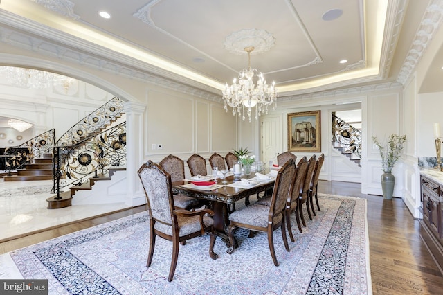 dining area featuring a chandelier, stairway, a tray ceiling, ornamental molding, and a decorative wall