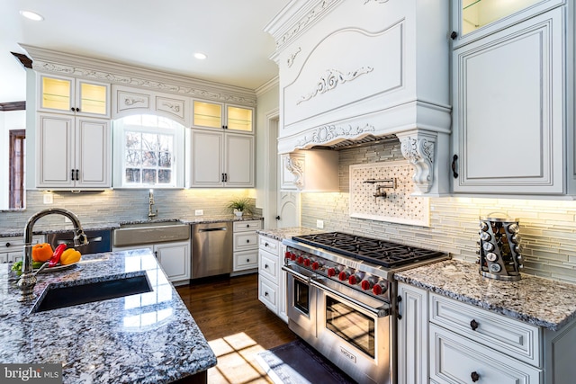 kitchen with backsplash, light stone countertops, stainless steel appliances, and a sink