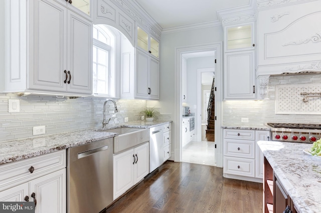 kitchen with dark wood-type flooring, ornamental molding, white cabinets, stainless steel appliances, and a sink