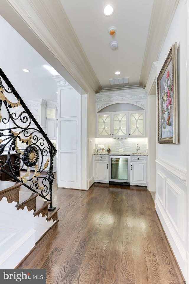 interior space featuring dark wood-style floors, recessed lighting, a sink, stairs, and ornamental molding