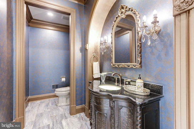 bathroom with visible vents, toilet, a sink, crown molding, and baseboards