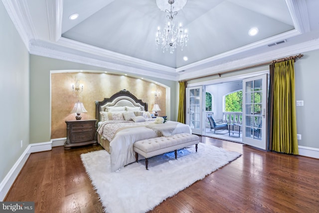 bedroom with a notable chandelier, wood finished floors, a tray ceiling, and access to outside