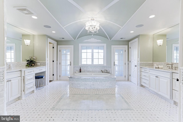 bathroom featuring a bath, a wealth of natural light, lofted ceiling, and an inviting chandelier