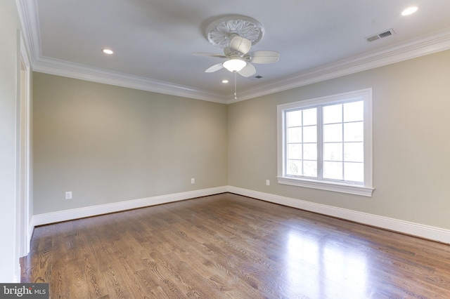 spare room with visible vents, a ceiling fan, wood finished floors, crown molding, and baseboards