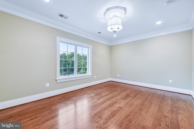 unfurnished room with wood finished floors, visible vents, baseboards, an inviting chandelier, and crown molding