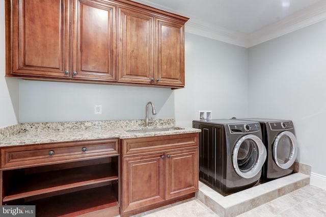 clothes washing area featuring washing machine and clothes dryer, wet bar, cabinet space, ornamental molding, and a sink