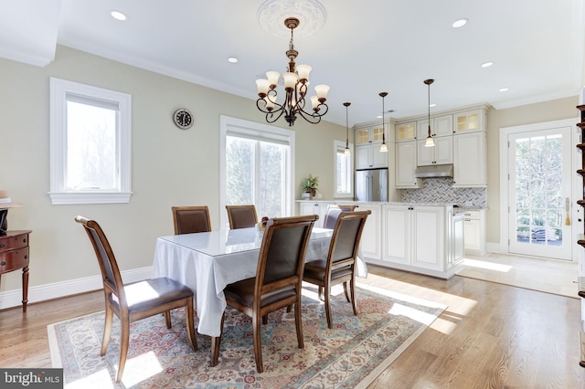 dining area with crown molding, plenty of natural light, light wood finished floors, and a chandelier