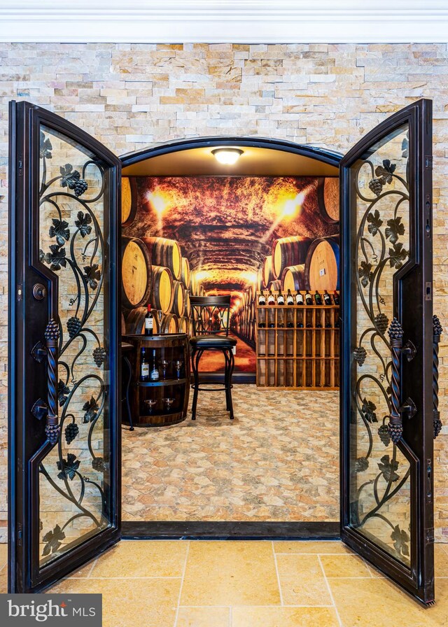 wine area featuring stone finish flooring and ornamental molding