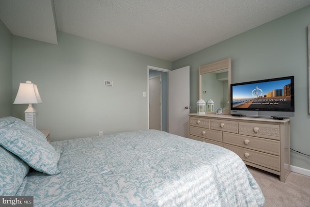 bedroom featuring light carpet and a textured ceiling