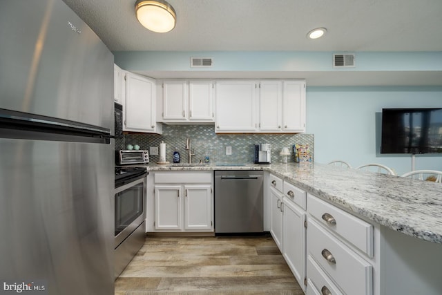 kitchen featuring a sink, stainless steel appliances, backsplash, and visible vents