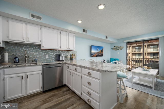 kitchen with dishwasher, a peninsula, visible vents, and white cabinetry