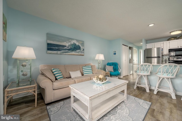 living room with recessed lighting, a textured ceiling, baseboards, and wood finished floors