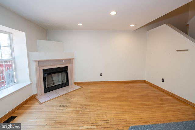 unfurnished living room featuring a tiled fireplace, recessed lighting, light wood-style flooring, and baseboards