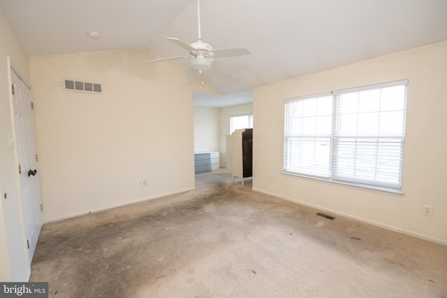 carpeted spare room featuring lofted ceiling, baseboards, and visible vents