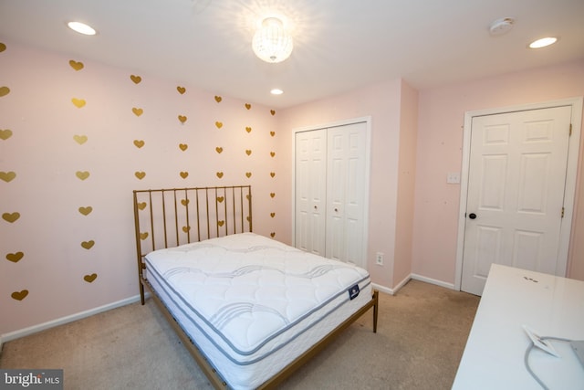 bedroom with a closet, recessed lighting, light colored carpet, and baseboards