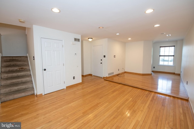 empty room with visible vents, recessed lighting, light wood-style floors, baseboards, and stairs