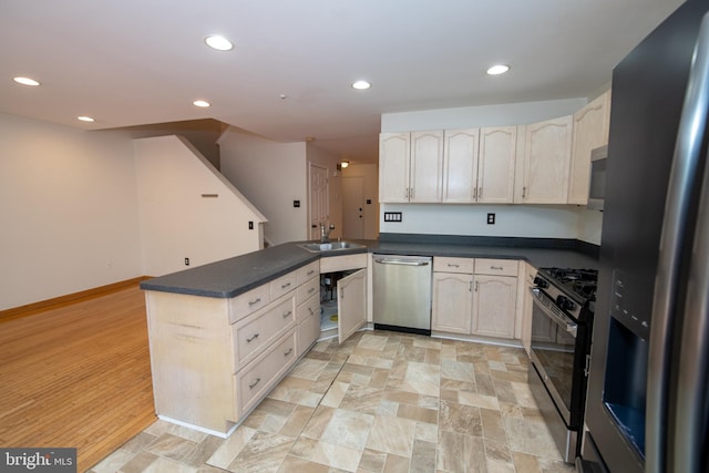 kitchen with dark countertops, a peninsula, stainless steel appliances, and a sink