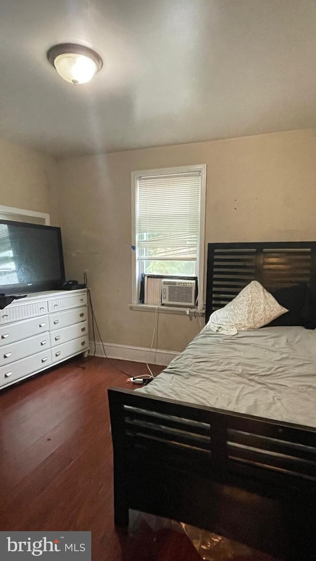 bedroom featuring cooling unit, baseboards, and wood finished floors