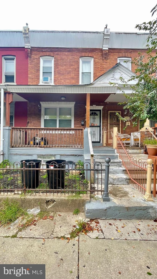 view of property with brick siding, covered porch, and a fenced front yard