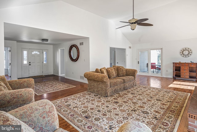 living area with baseboards, wood finished floors, visible vents, and high vaulted ceiling