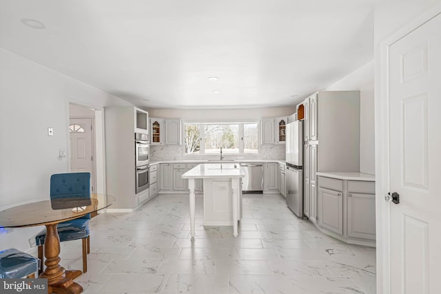 kitchen featuring a center island, tasteful backsplash, marble finish floor, and stainless steel appliances