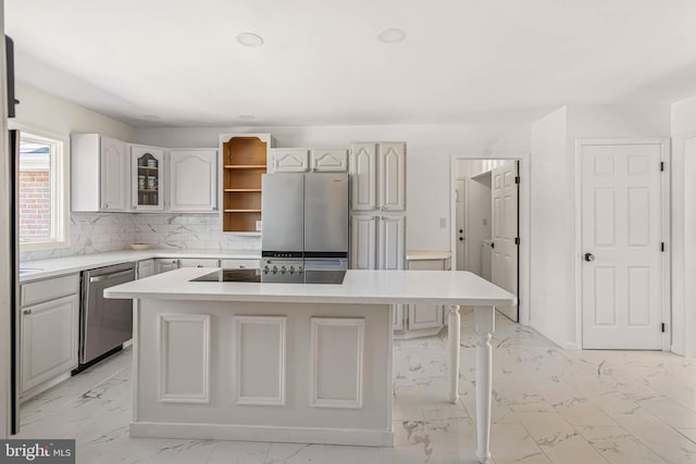 kitchen with backsplash, a kitchen island, light countertops, appliances with stainless steel finishes, and marble finish floor