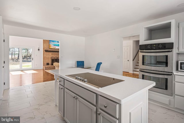 kitchen with open floor plan, marble finish floor, stainless steel appliances, and light countertops